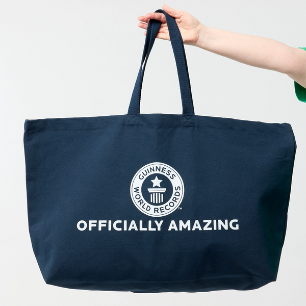 Oversized Guinness World Records navy tote bag with model hand holding it up 