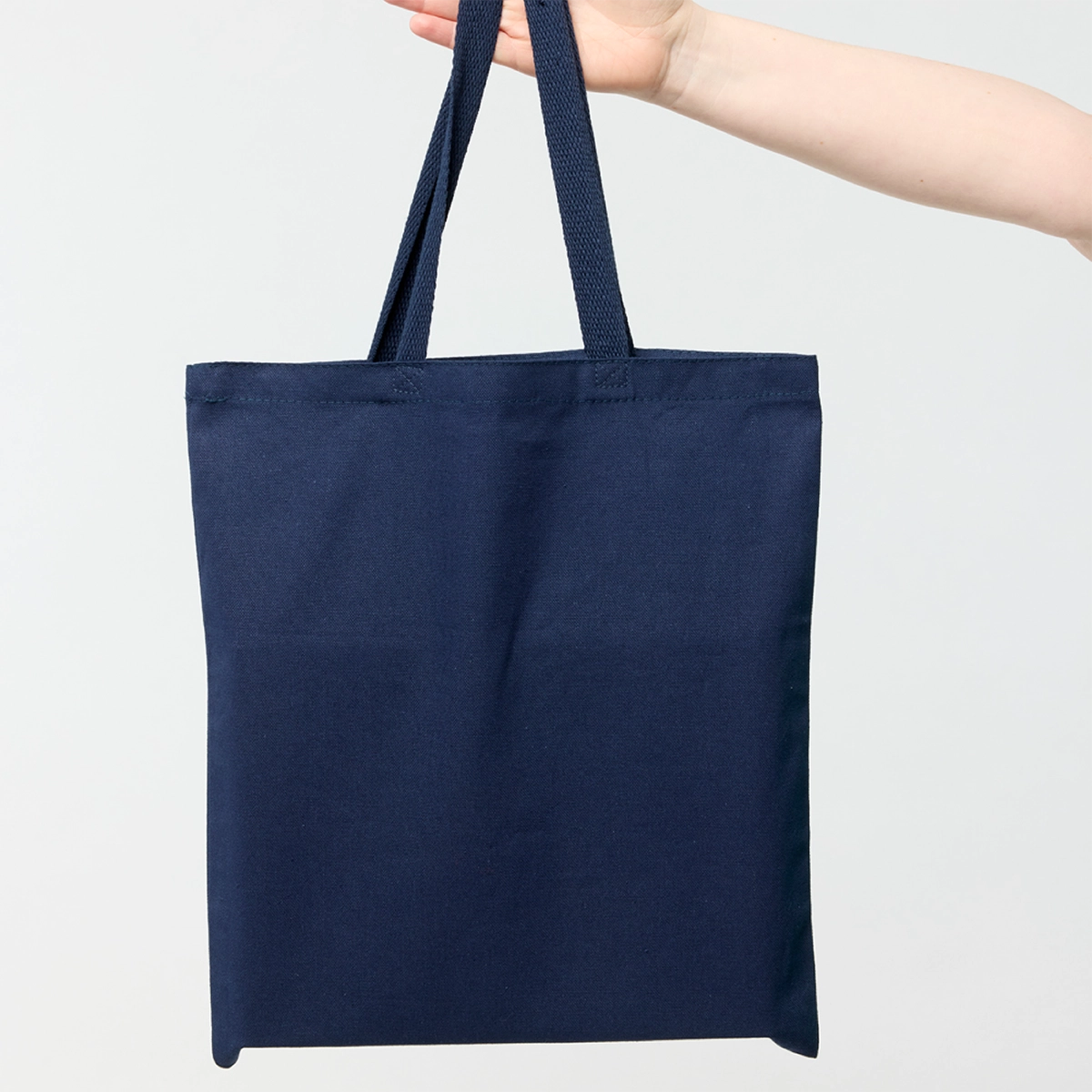 reverse side of navy tote bag being held by a model 