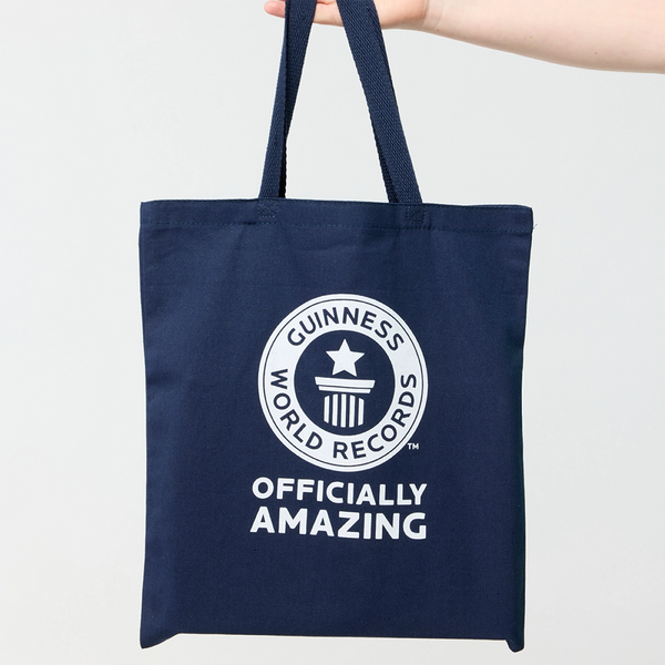 Navy tote bag with Guinness World Records logo and Officially Amazing text being held by a model 