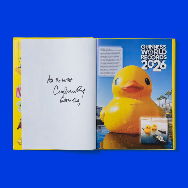 Open book showing a page from 'Guinness World Records 2026' with signature of the book editor and a large yellow rubber duck on a blue background.