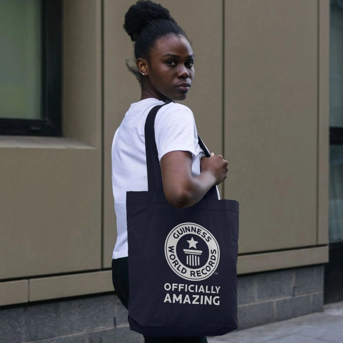 Woman holding a black tote bag with star and pedestal logo