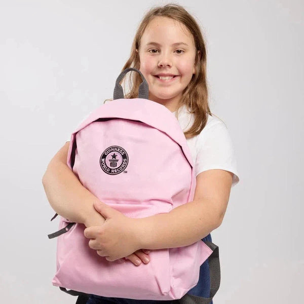 Girl holding a pink backpack with a black GWR logo on a light gray background