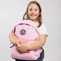 Girl holding a pink backpack with a black GWR logo on a light gray background