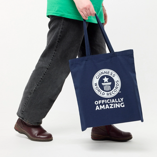 Person holding a navy tote bag with Guinness World Records logo on a white background